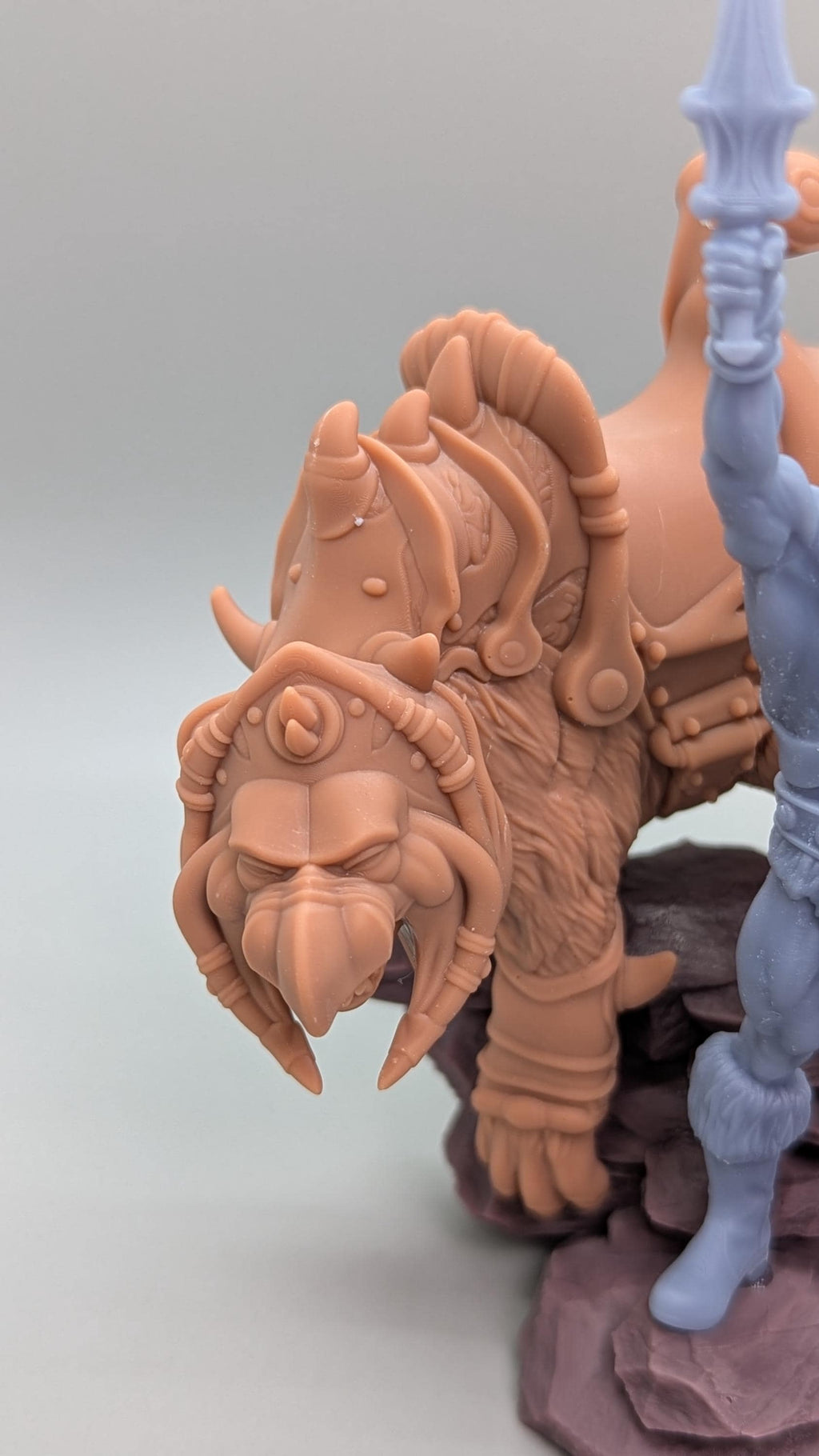A detailed figurine of a fierce-looking creature with horns and a fierce expression, sitting on a rock formation.