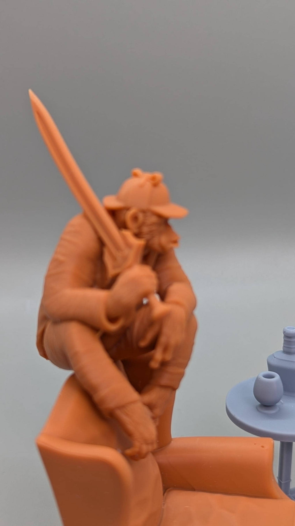 a figurine of a person sitting in a chair, holding a sword in their hand.