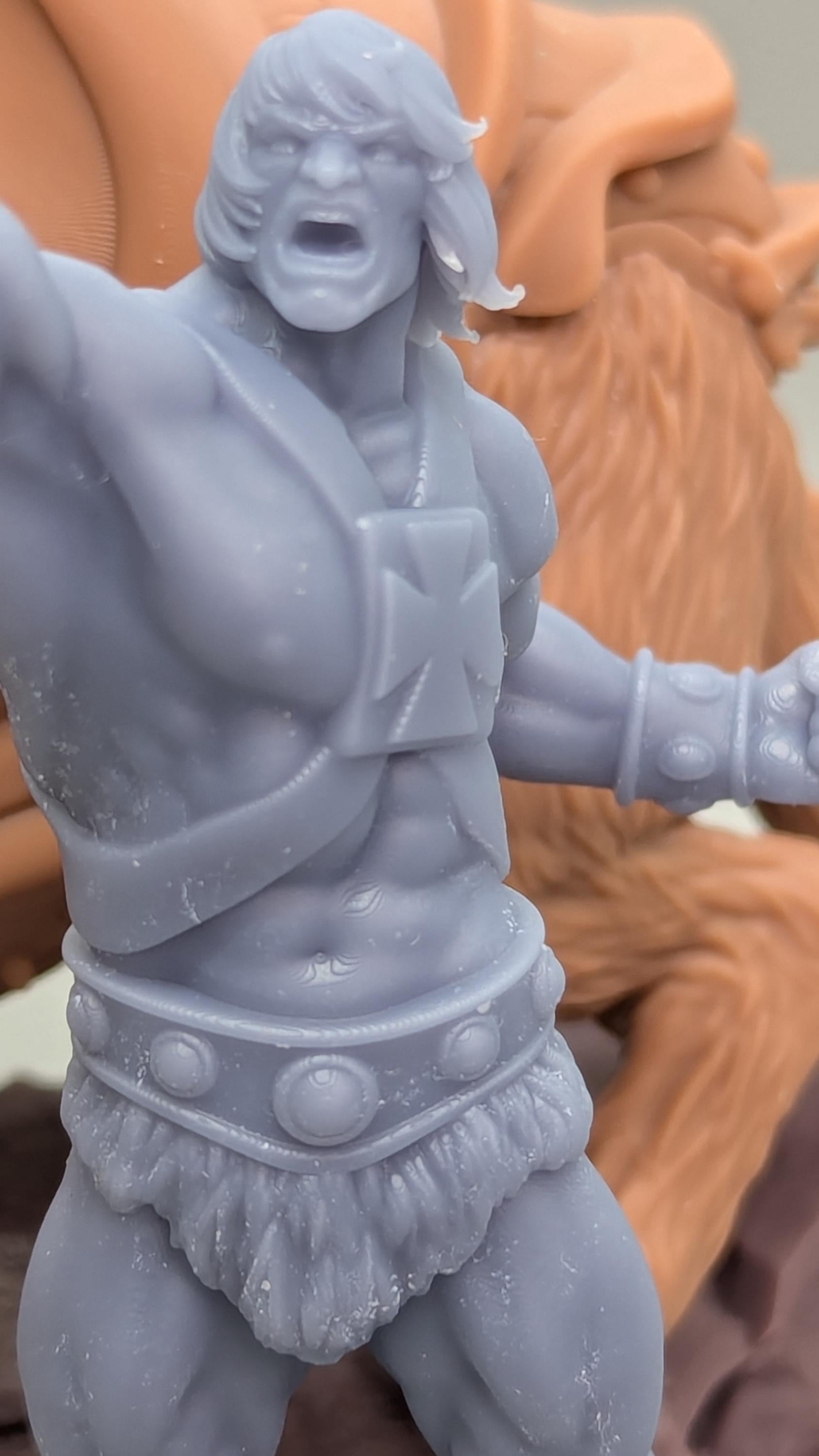 A close-up image of a figurine of a muscular, bearded man with a determined expression, wearing a belt with circular buttons.