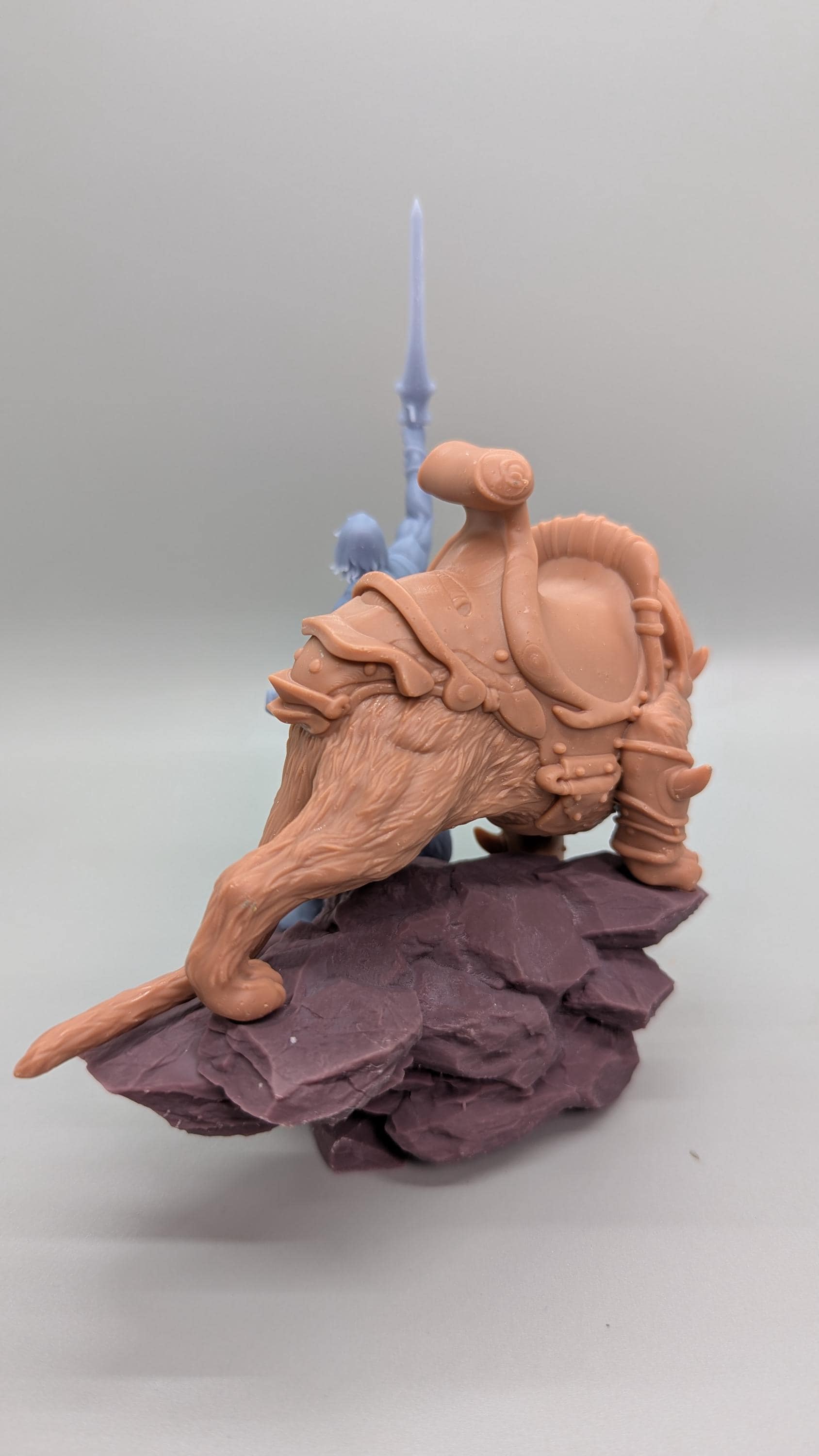 A figurine of a brown dragon-like creature with a saddle on its back, standing on a rock formation.