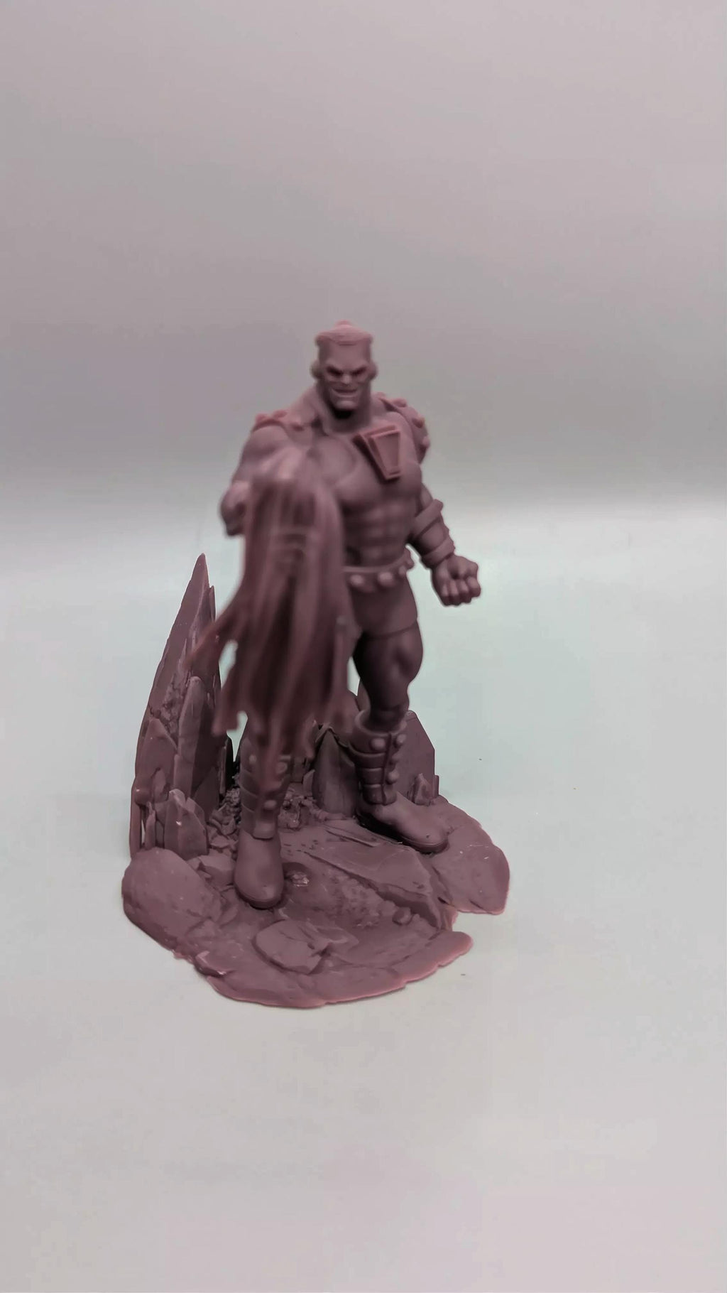 A figurine of a muscular, bald, and bearded man standing on a rocky base.