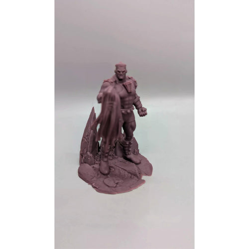 A figurine of a muscular, bald, and bearded man standing on a rocky base.