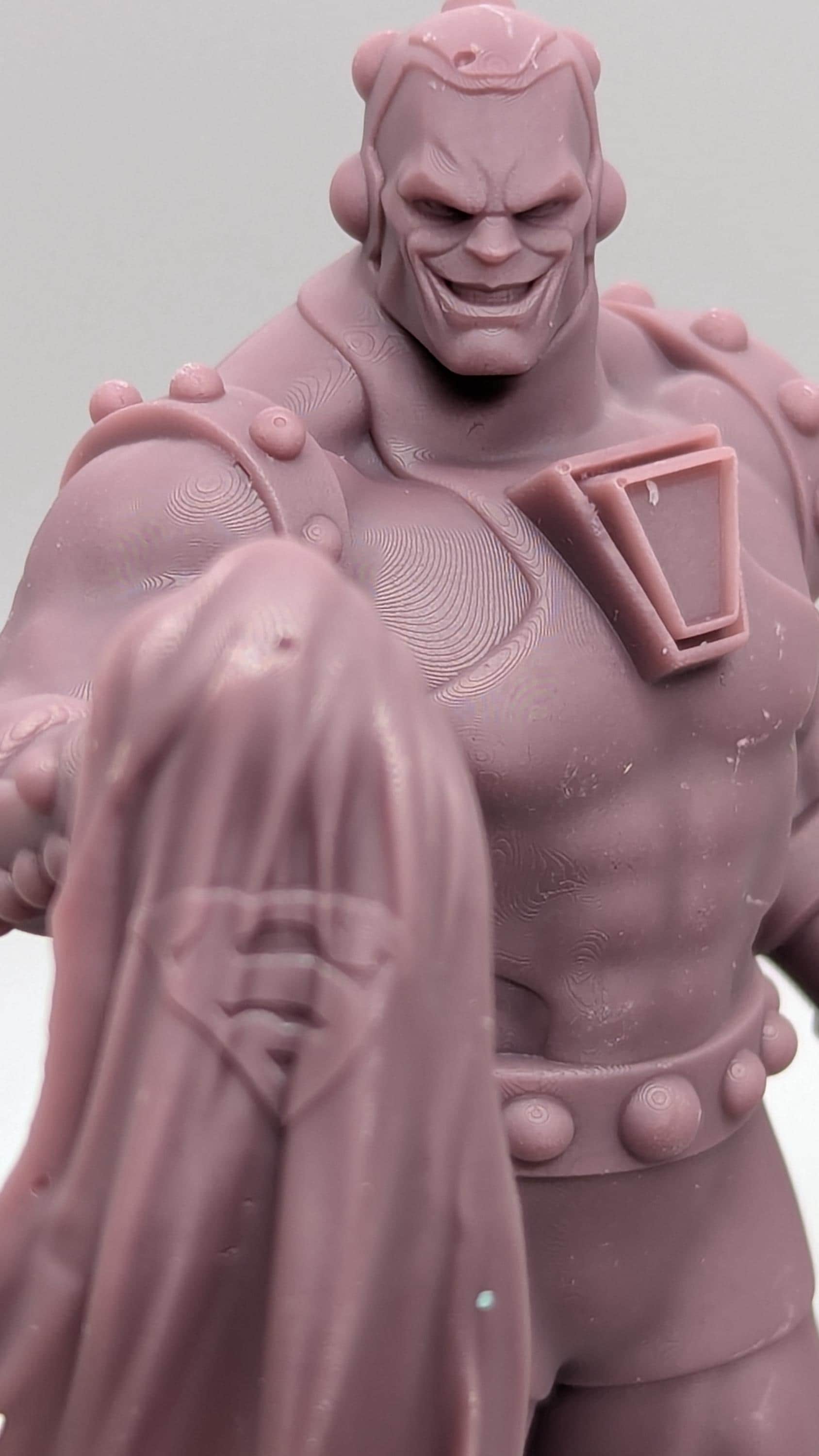 A close-up image of a pink plastic figurine depicting a muscular, muscular-looking character with a stern expression.