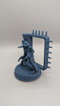 A figurine of a person in a hat and coat, standing on a platform with a rectangular frame attached to it.