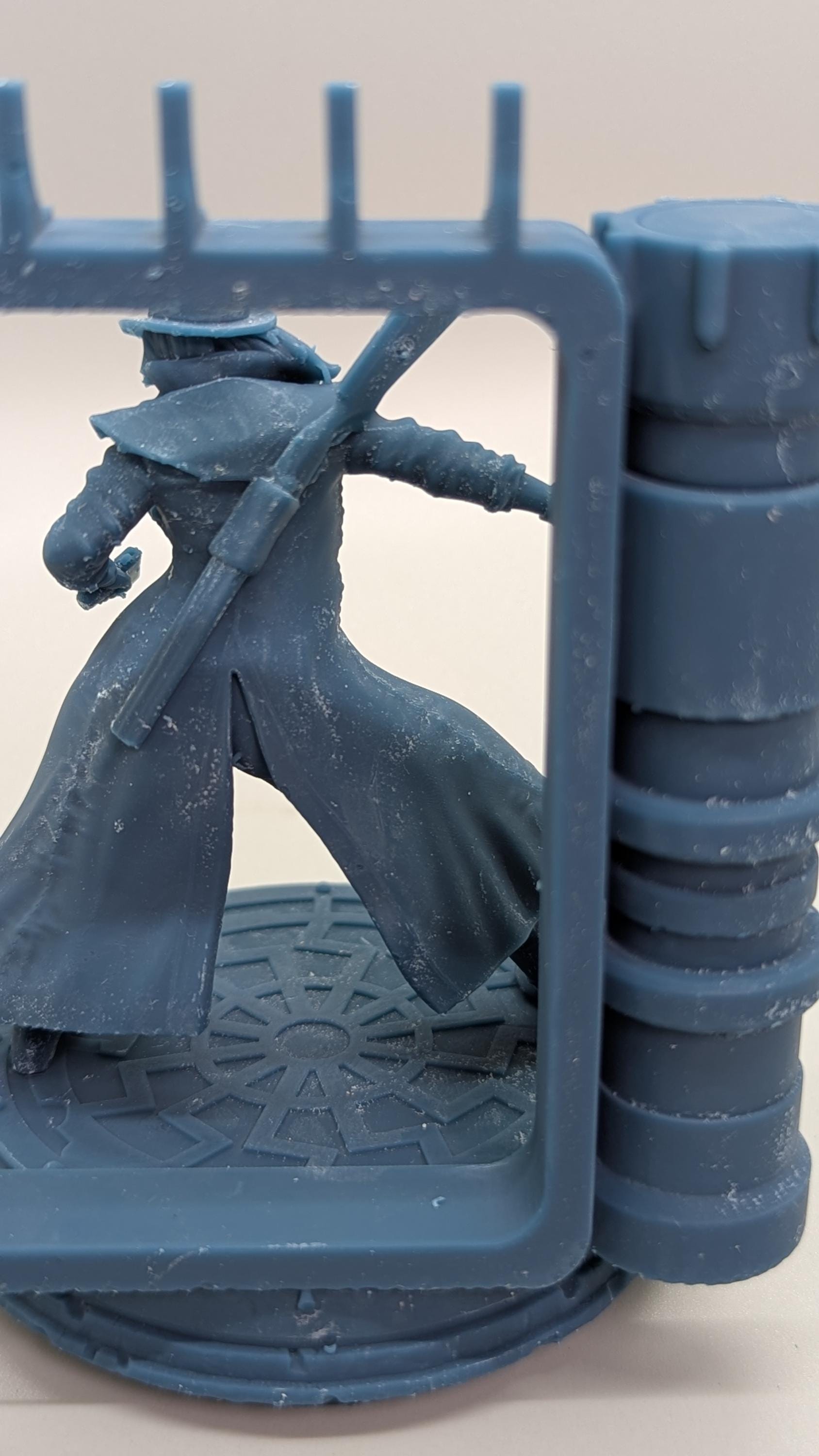 A figurine of a person in a long coat and hat, holding a sword, is displayed in a blue frame.