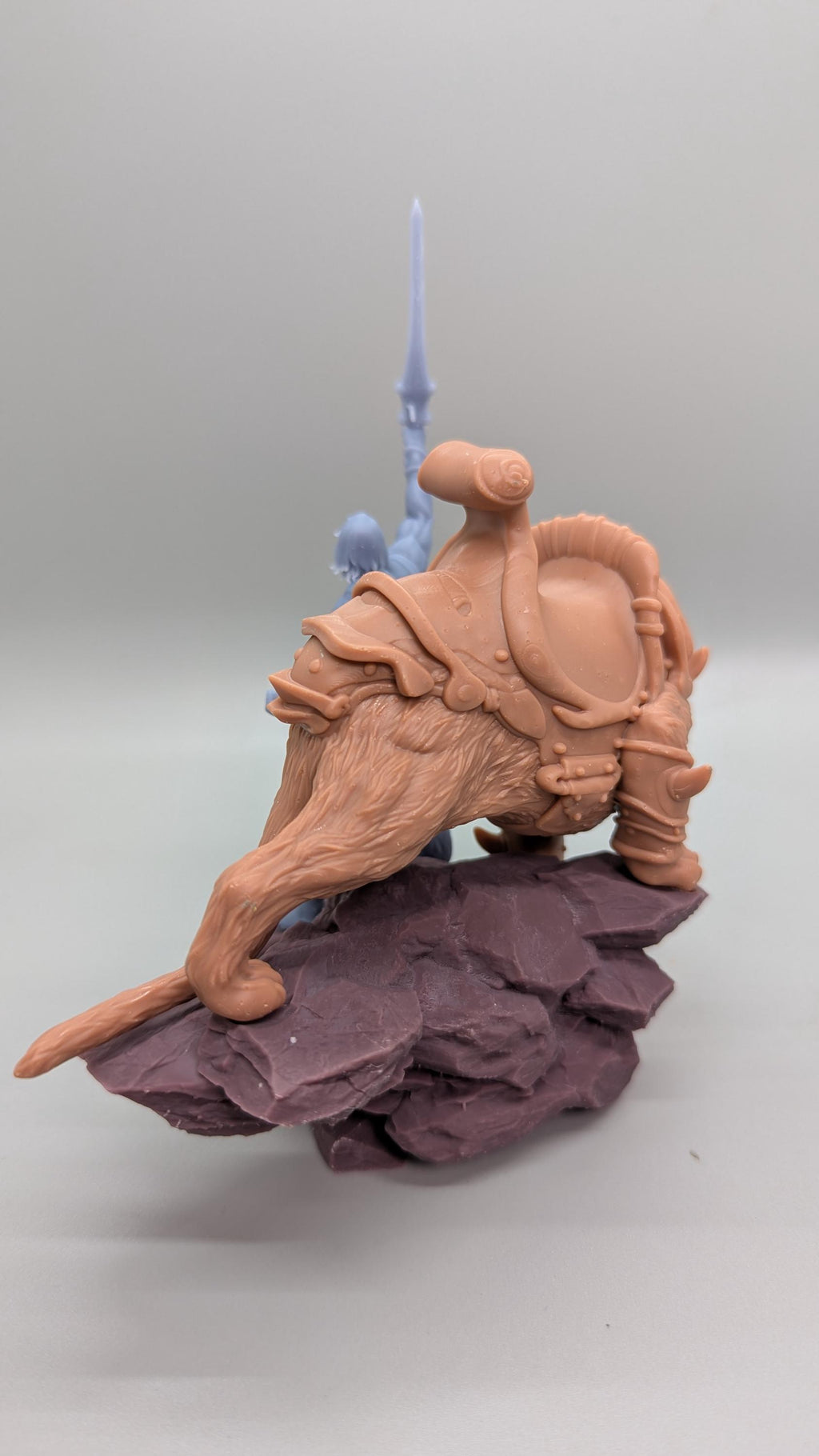 A figurine of a brown dragon-like creature with a saddle on its back, standing on a rock formation.