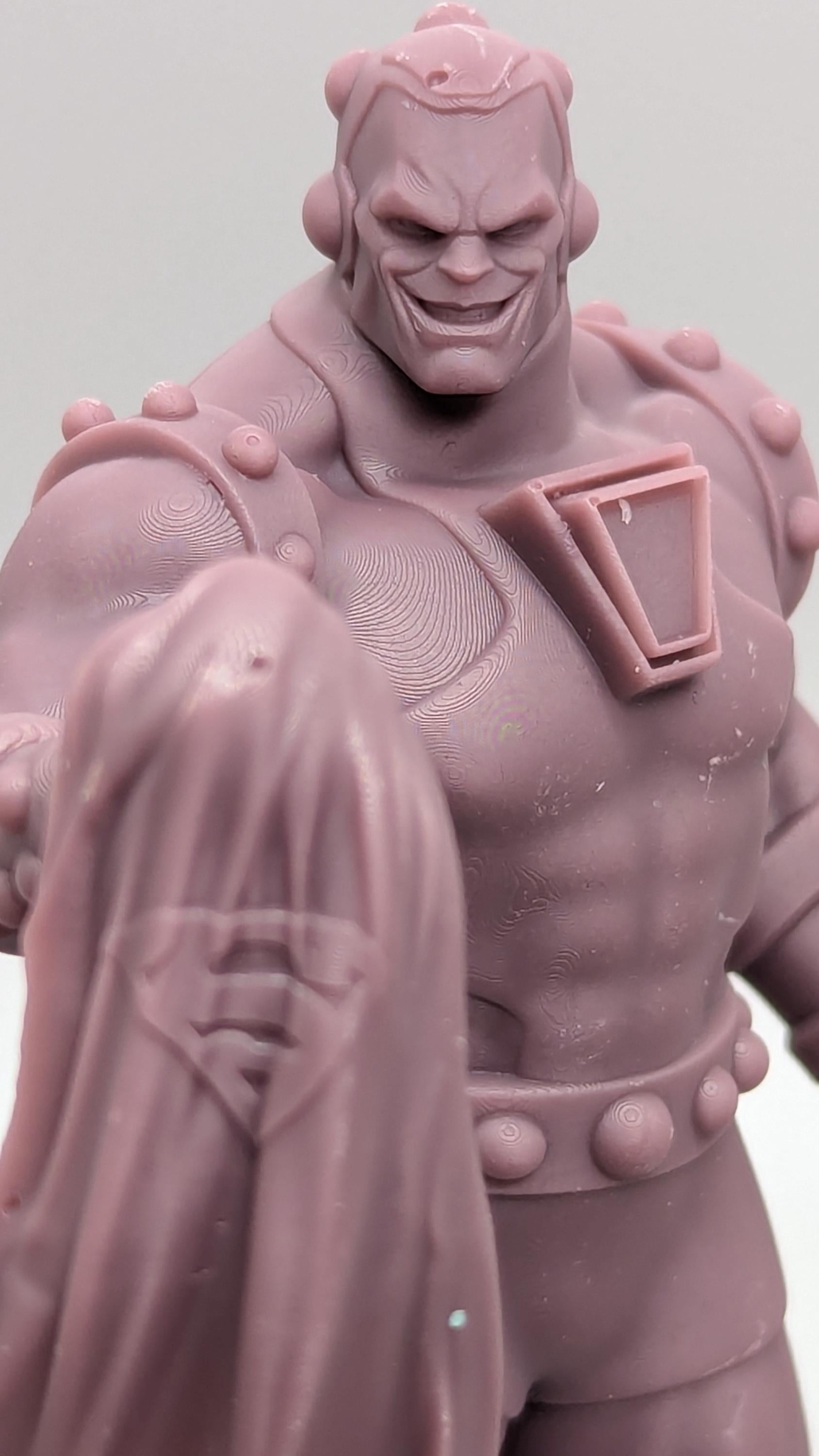 A close-up image of a pink plastic figurine depicting a muscular superhero character with a determined expression.