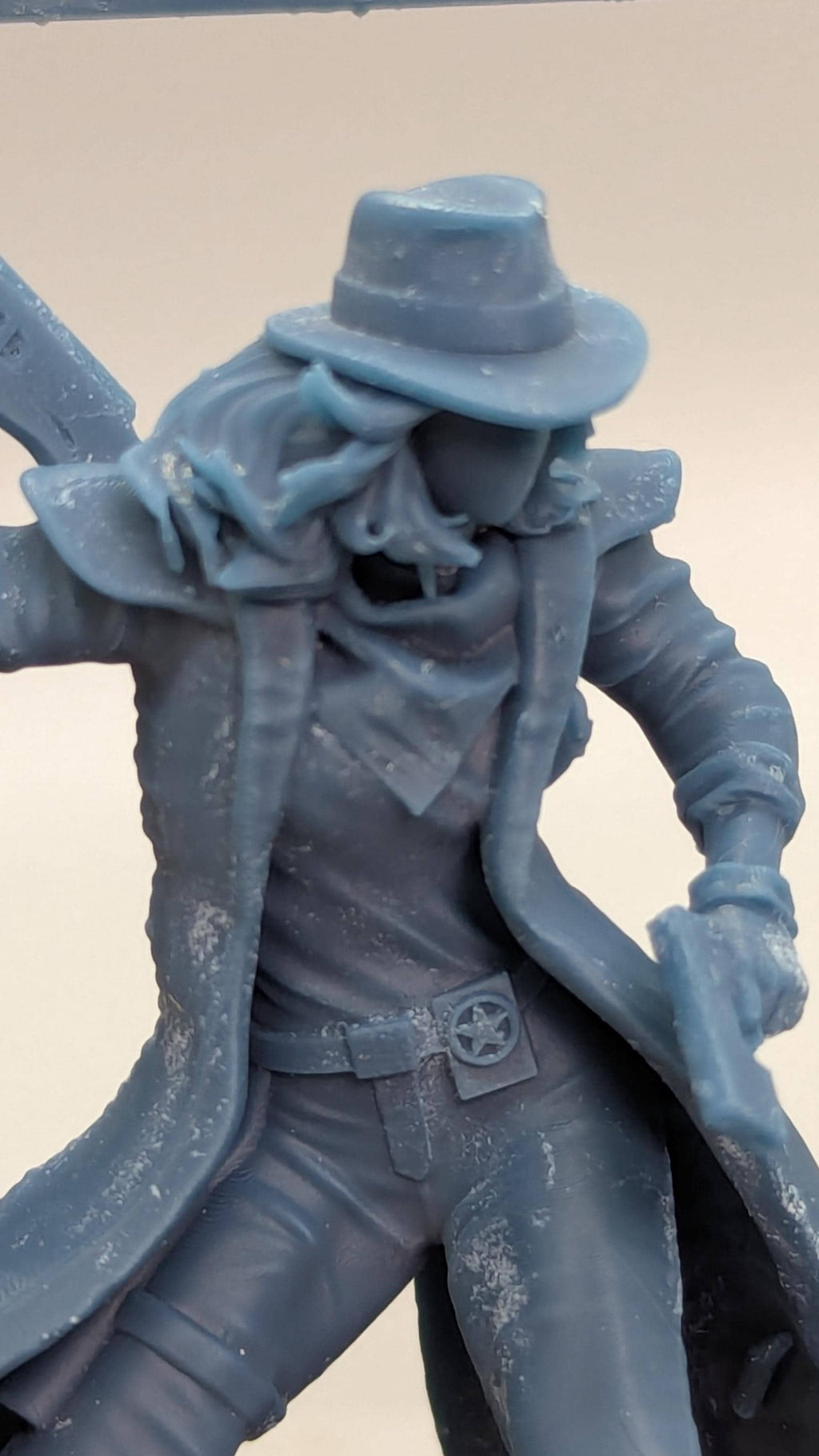 A close-up view of a figurine or statue depicting a person wearing a hat and coat, with a star emblem on the belt.