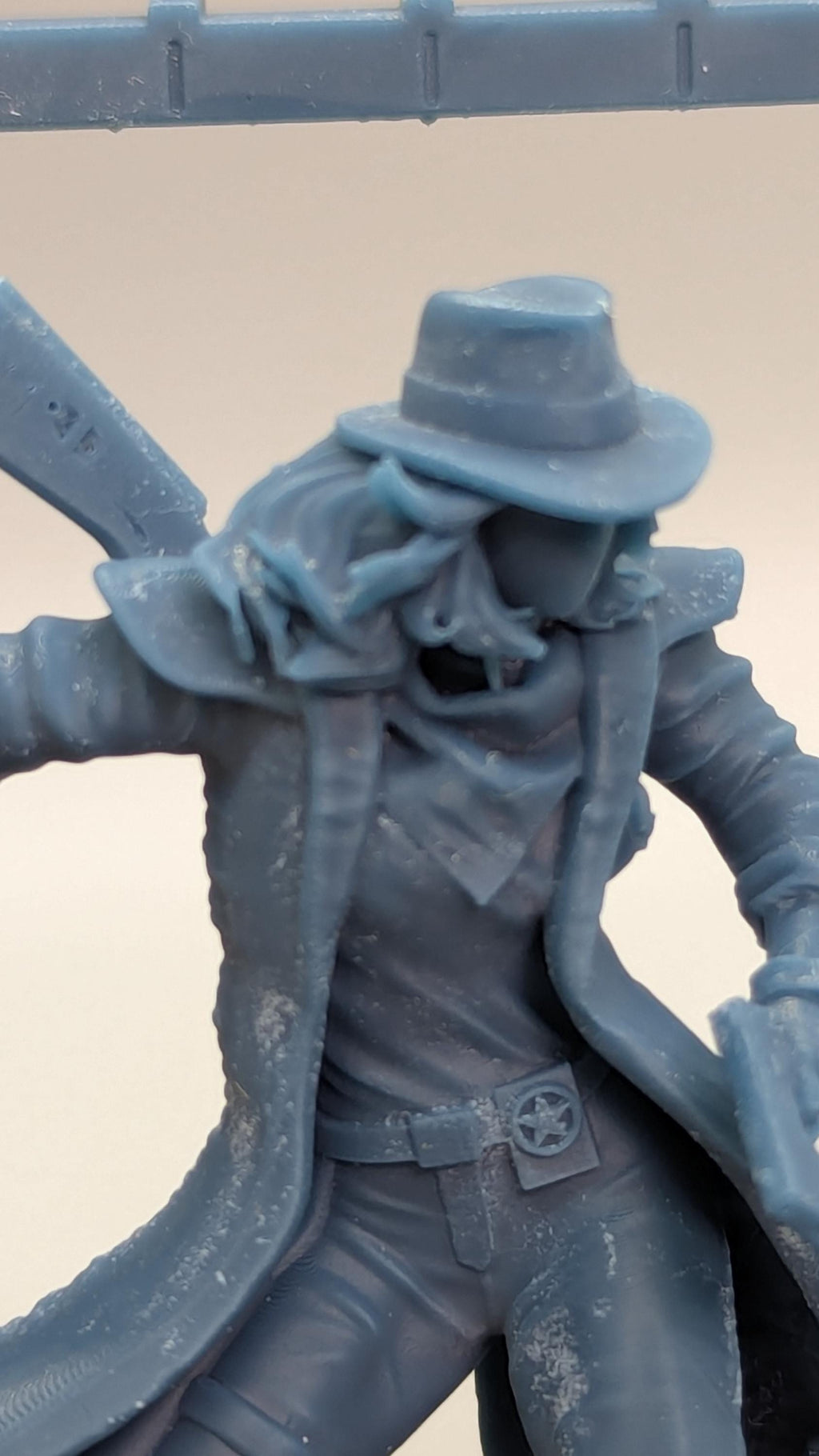 A close-up view of a figurine or toy in a dark blue color, with a hat and a gun visible.