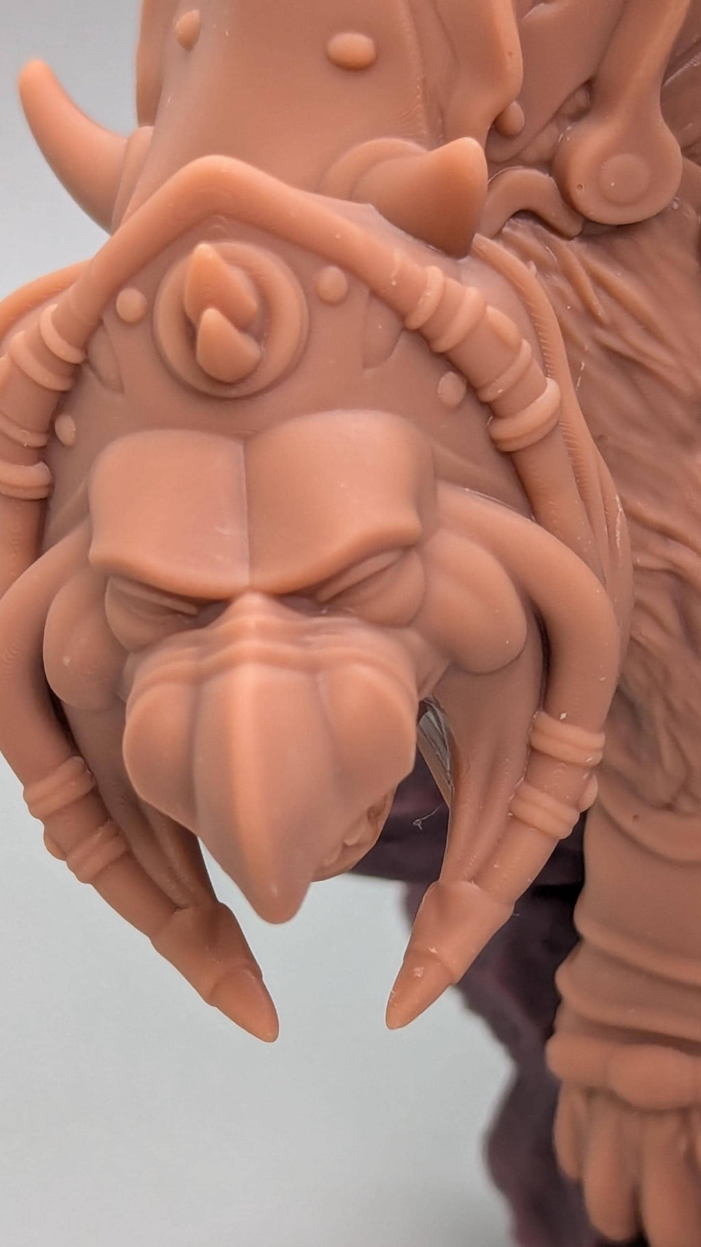 A close-up view of a detailed, sculpted figurine depicting a fierce-looking creature with sharp teeth and claws.