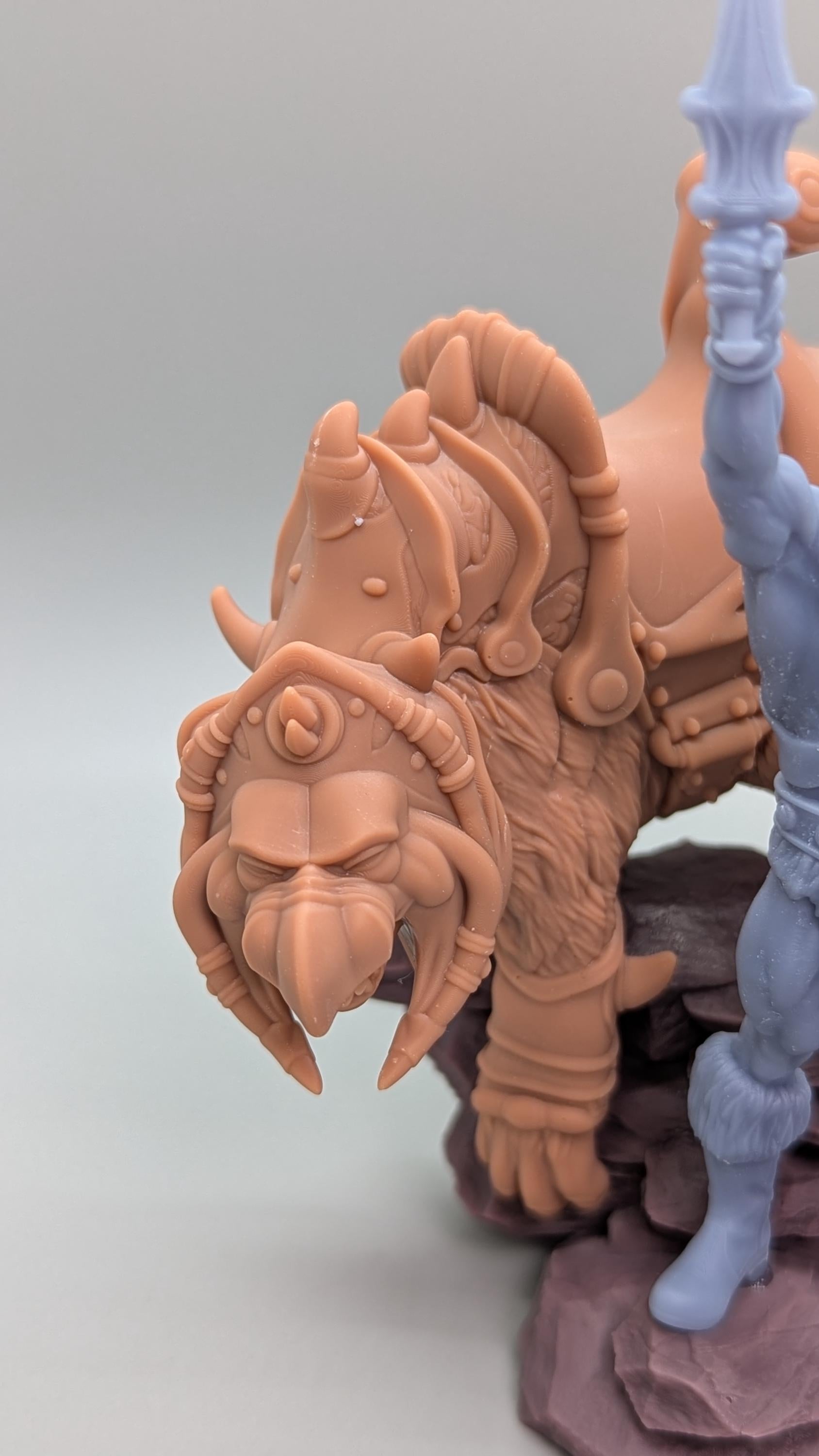 A detailed figurine of a fierce-looking creature with horns and a fierce expression, sitting on a rock formation.