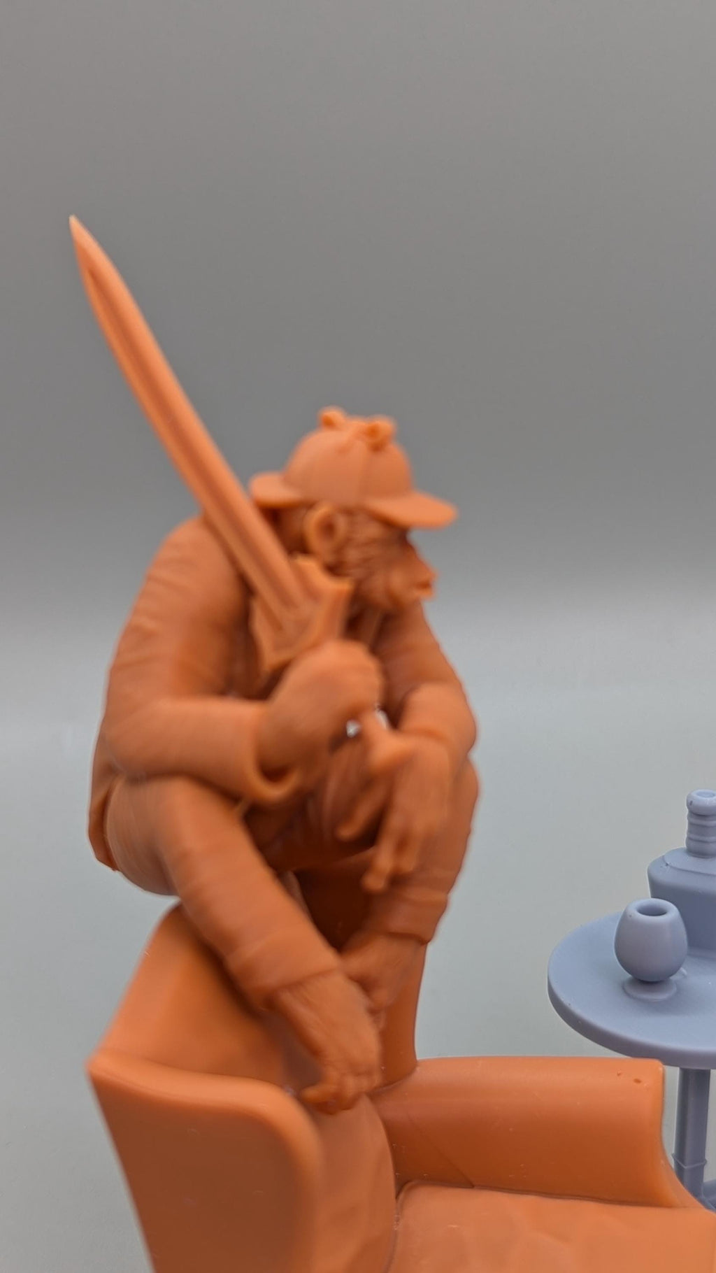 a figurine of a person sitting in a chair, holding a sword in their hand.