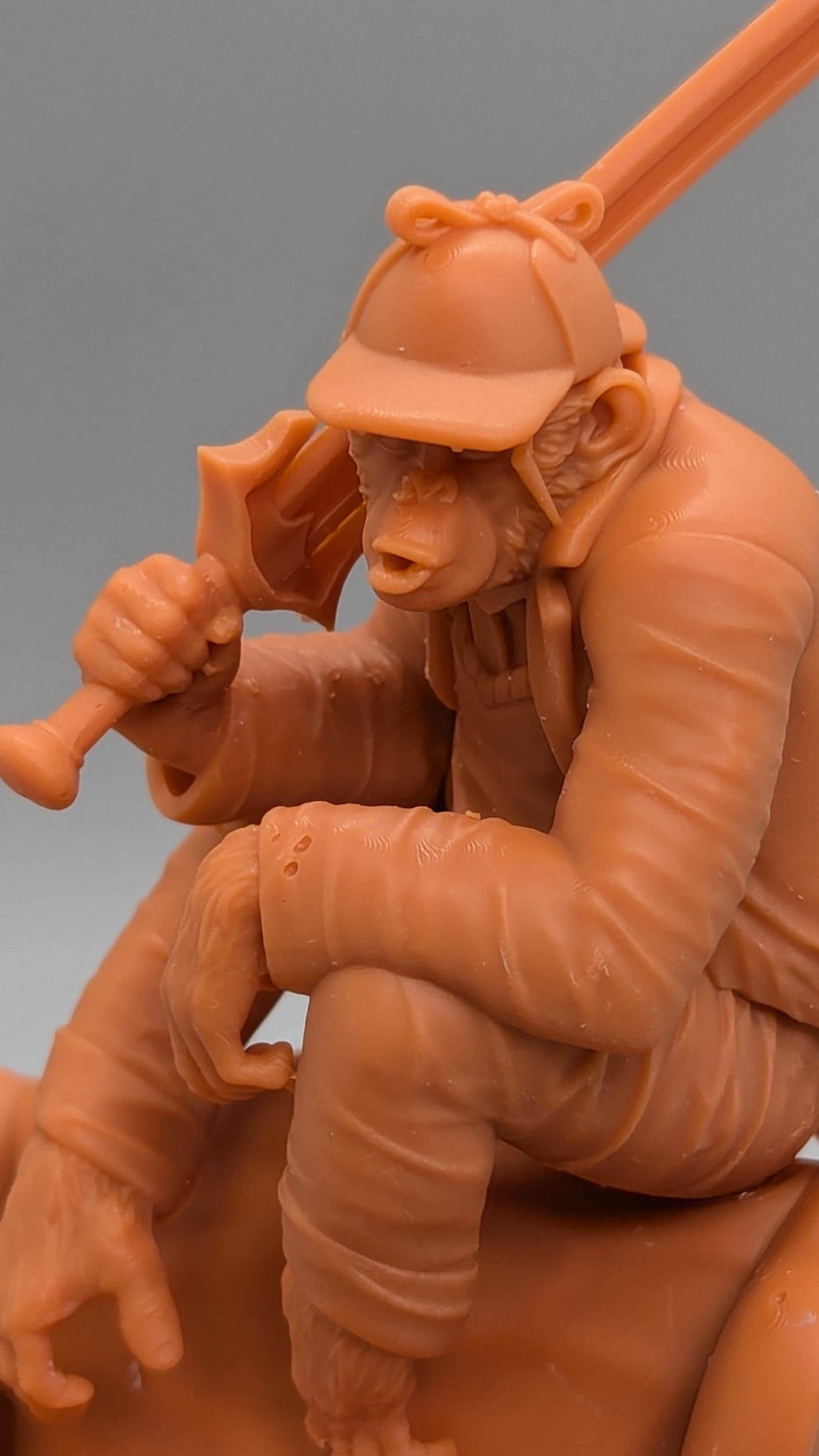 A figurine of a monkey holding a baseball bat and sitting on a rock.