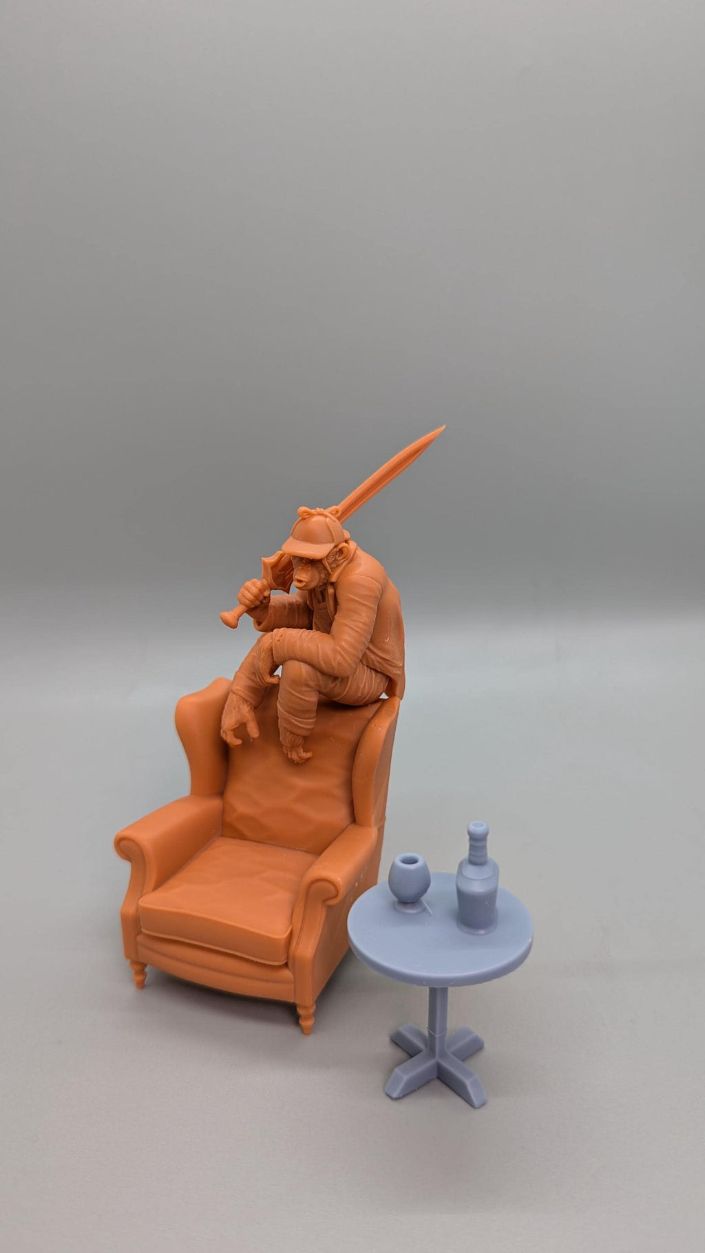 a small figurine of a person sitting in a chair, holding a sword, and a small table with two bottles on it.